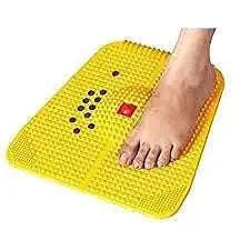 Acupressure magnet mat with yellow pyramid spikes, foot resting on surface
